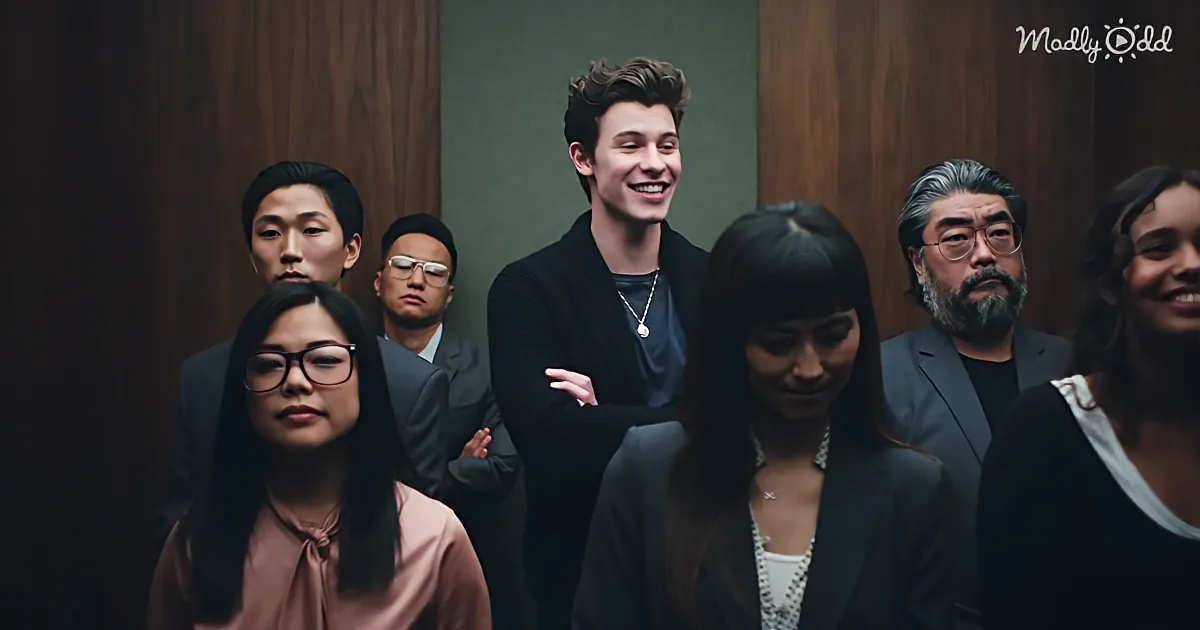 Shawn Mendes smiles confidently with arms crossed, surrounded by a diverse group of people in a formal setting.