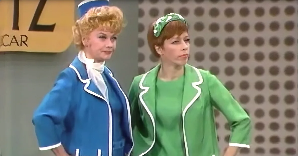 Two women in retro uniforms, one in blue, the other in green, stand side by side.