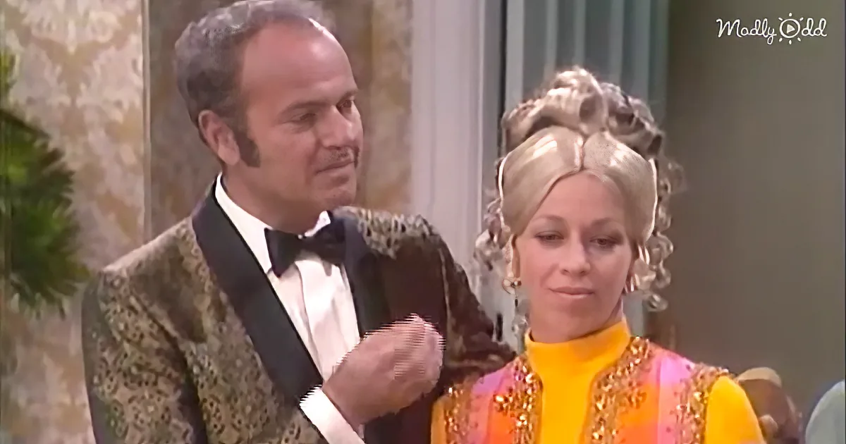 A man in a tuxedo adjusts a woman's necklace in a formal setting.