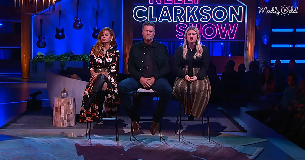 Three people sit on stage in front of a neon sign reading "Kelly Clarkson Show," with guitars and plants in the background.