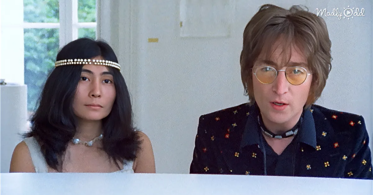 A woman with long dark hair and a pearl headband sits next to a man with glasses and a patterned jacket.