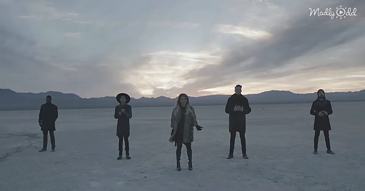Five people stand in a vast, flat desert landscape under a dramatic sky.