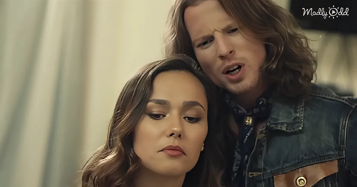 A woman with long brown hair sits calmly while a man with long hair leans over her, appearing distressed.