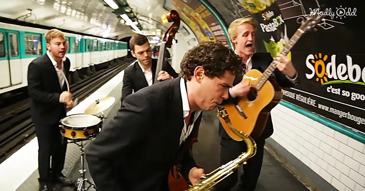 A man in a suit plays a saxophone in a subway station, surrounded by other musicians.