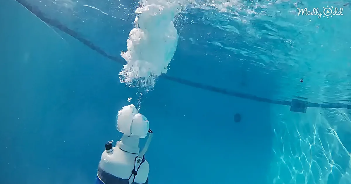 A white underwater camera captures a diver's bubbles rising in a clear blue pool.