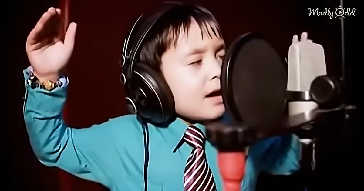 A person wearing headphones and a blue shirt with a striped tie is singing into a microphone.