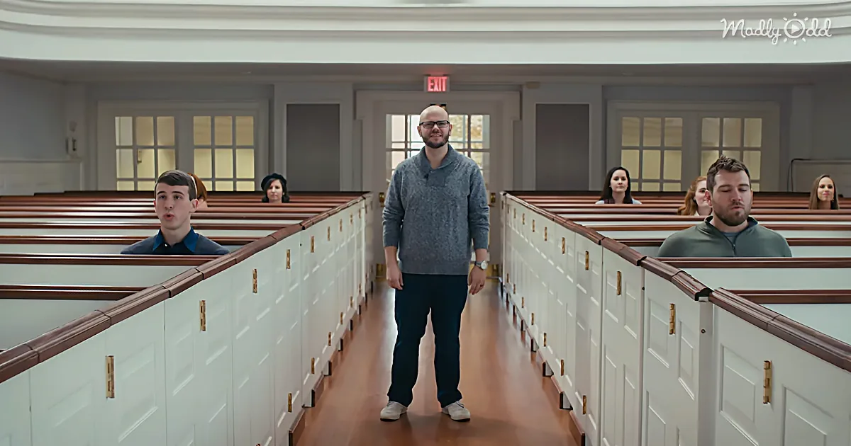 A man stands in the aisle of a church, surrounded by pews and people, with an "EXIT" sign above.
