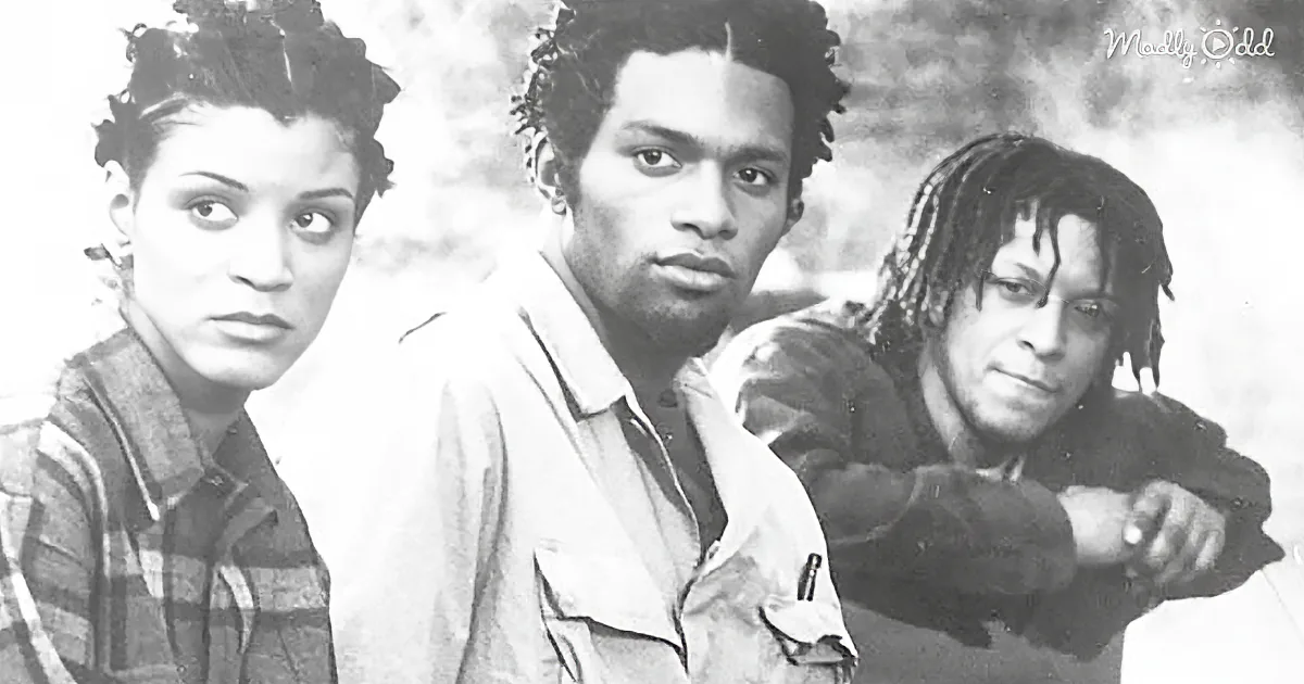 Three individuals, two with dreadlocks, sit closely together in a black-and-white image.