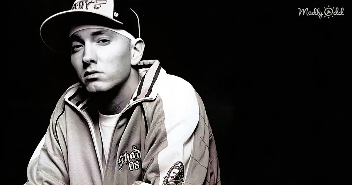 A person wearing a cap and jacket, looking to the side, with a dark background and "Madly Odd" text in the corner.