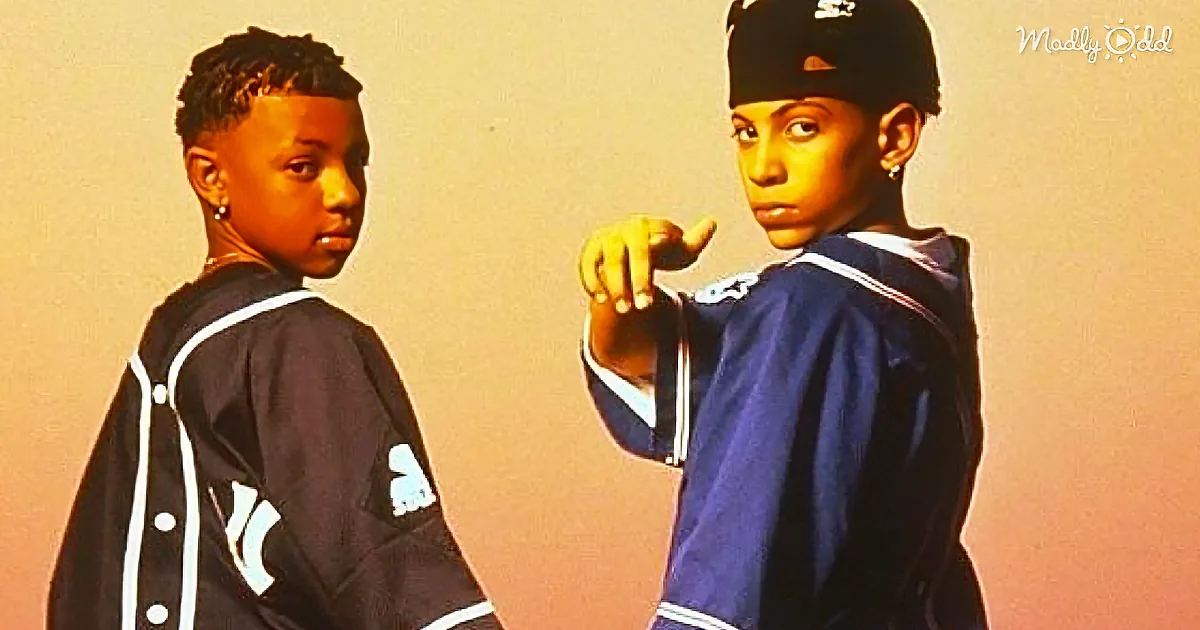 Two individuals in matching blue jackets pose confidently, one pointing forward, against a gradient background.