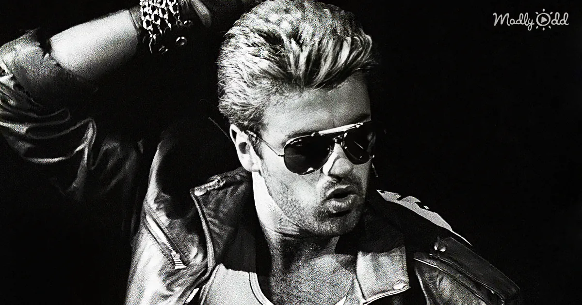 A man in a leather jacket and sunglasses, striking a confident pose against a dark background.