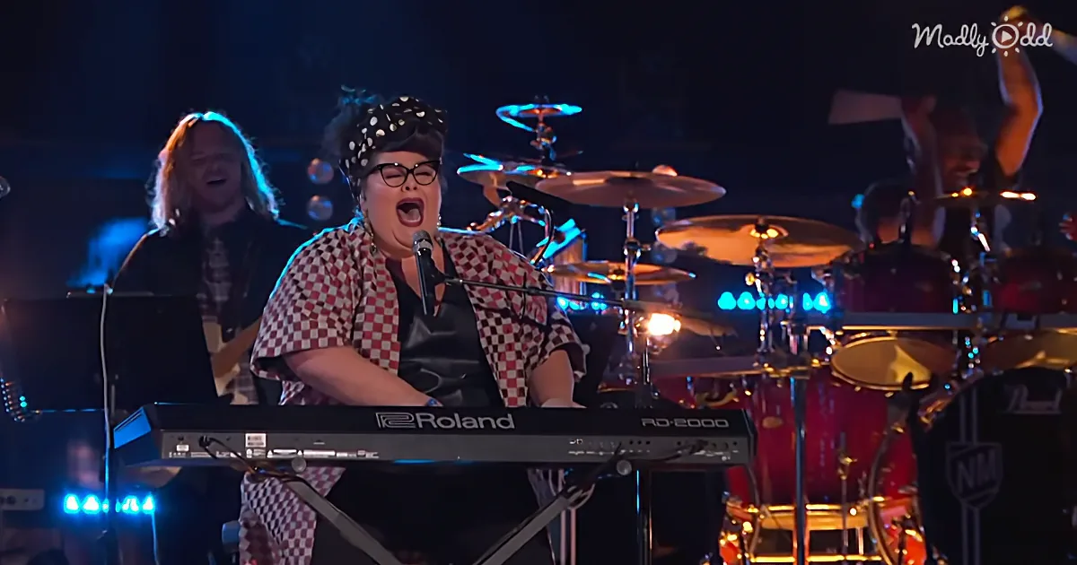 A person in a checkered outfit sings passionately while playing a Roland keyboard on stage.