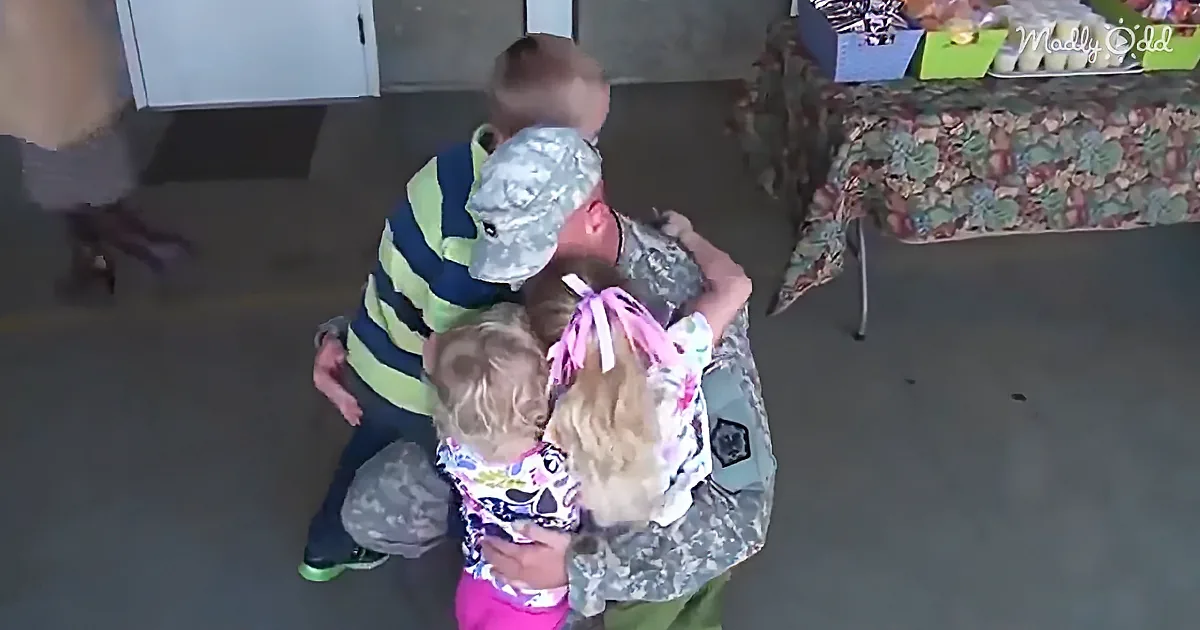 A soldier in camouflage embraces two children, one wearing a foil hat, in a heartfelt reunion.