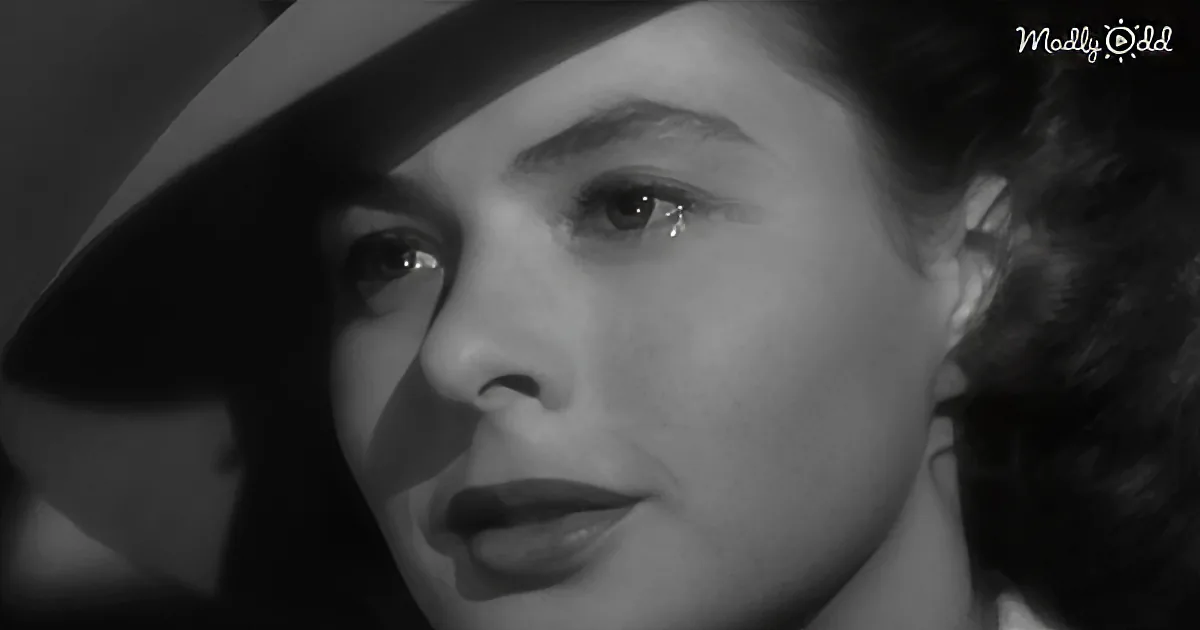 A close-up of a woman with dark hair and a hat, her face partially in shadow, conveying a somber mood.