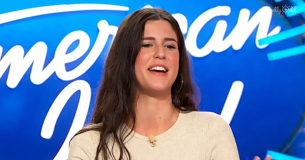 A woman with long dark hair smiles in front of a blue background with "American Idol" text.