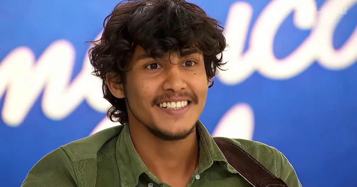 A smiling person with curly hair, wearing a green shirt, stands in front of a blue background with white text.