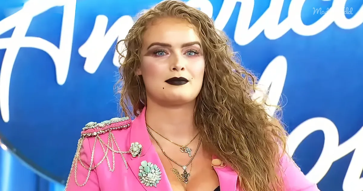 A person with curly hair, wearing a pink jacket with embellishments, stands in front of a blue background with white text.