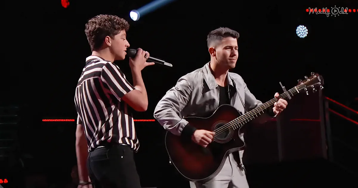 Two men perform on stage, one singing into a microphone, the other playing guitar.