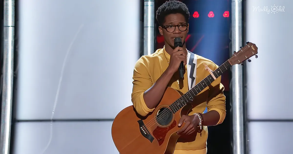 A person in a yellow outfit plays an acoustic guitar and sings into a microphone on stage.