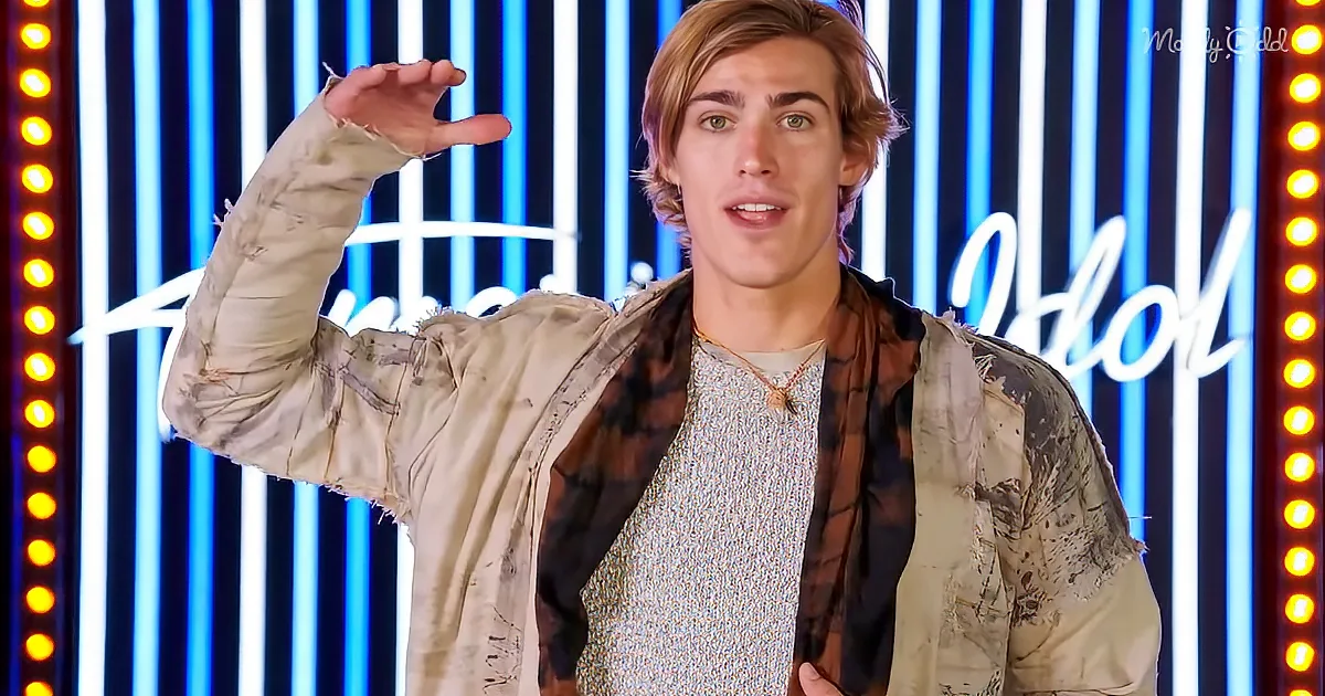 A person in a distressed jacket and plaid shirt gestures with their right hand in front of a neon-lit background.