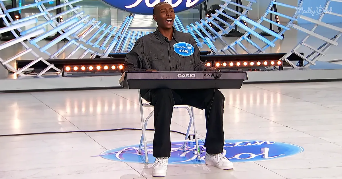 A man sits on a stool playing a Casio keyboard on an American Idol stage.