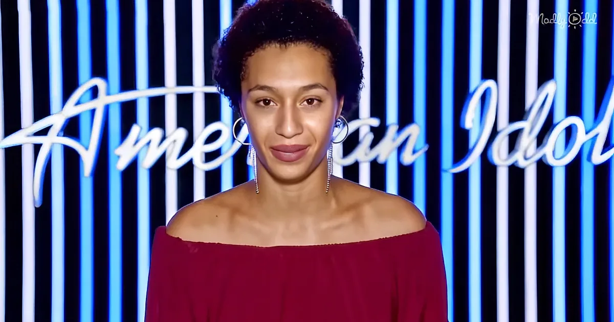 A woman in a red off-shoulder top stands in front of a blue and white striped background with "American Idol" text.