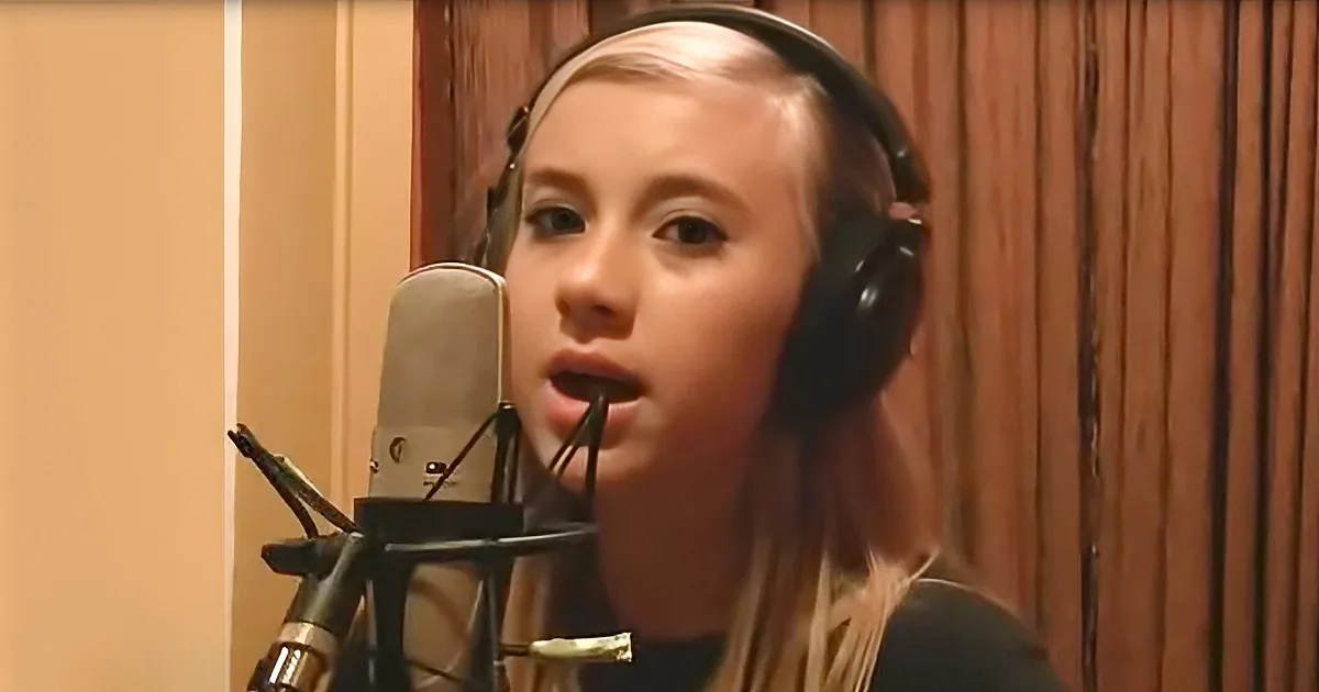 A person wearing headphones sings into a microphone in a recording studio.