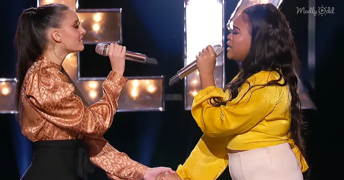 Two women sing on stage, one in gold, the other in yellow, holding microphones.