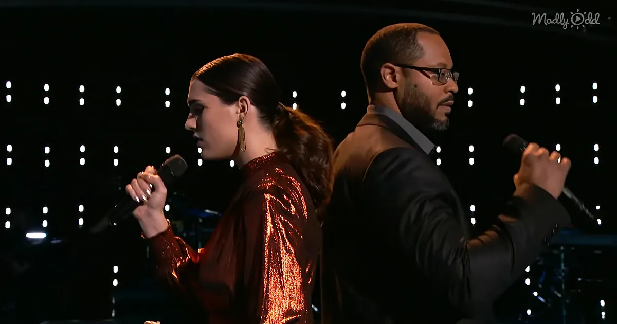 A woman in a sequined dress and a man in a suit sing into microphones on stage.
