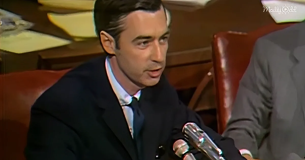 A man in a suit and tie is speaking into microphones at a formal event.
