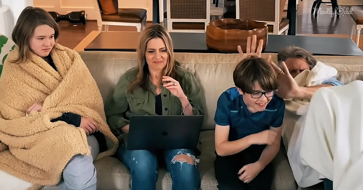 A family of four sits on a couch, with a woman in the middle using a laptop, while others react with various expressions.