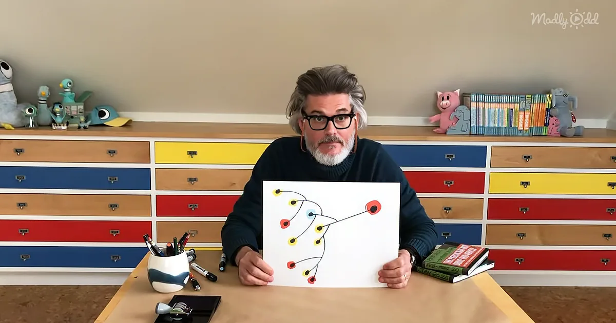 A person with glasses holds a drawing at a desk, surrounded by colorful drawers and toys.