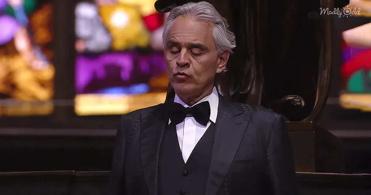 A man in a tuxedo with a bow tie stands in front of a colorful, festive background.