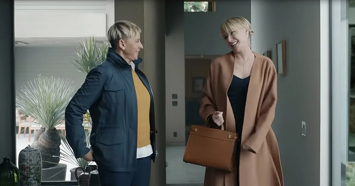 Two women in a modern home, one in a navy jacket and the other in a beige coat, smiling and interacting.