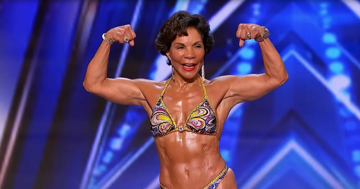 A woman in a bikini flexes her muscles on stage, showcasing her physique.