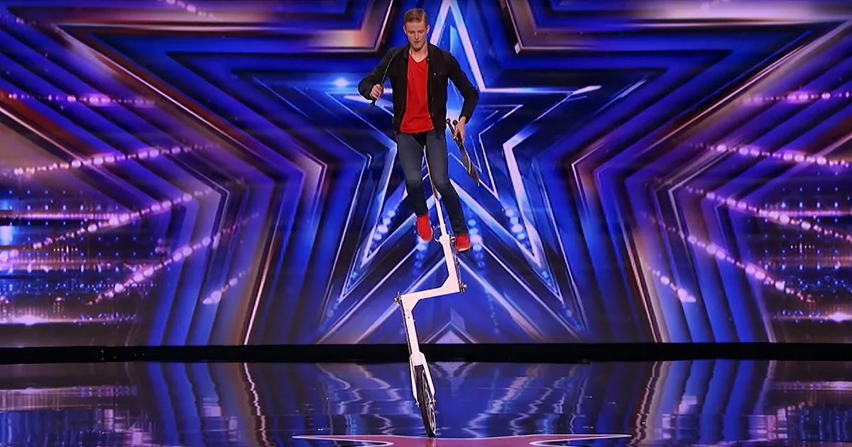 A man balances on a unicycle on a stage with a star-shaped background.