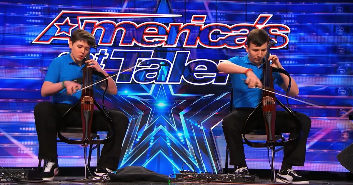 Two young men play violas on stage at America's Got Talent with a blue star background.