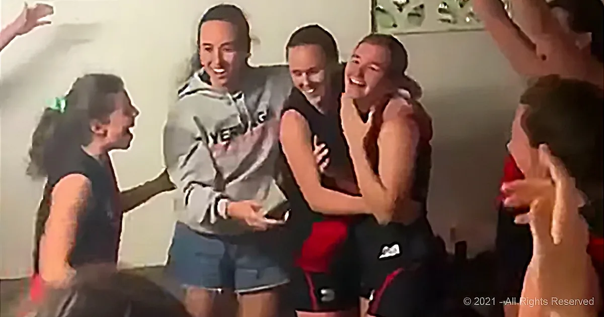 A group of people are laughing and interacting in a lively indoor setting.