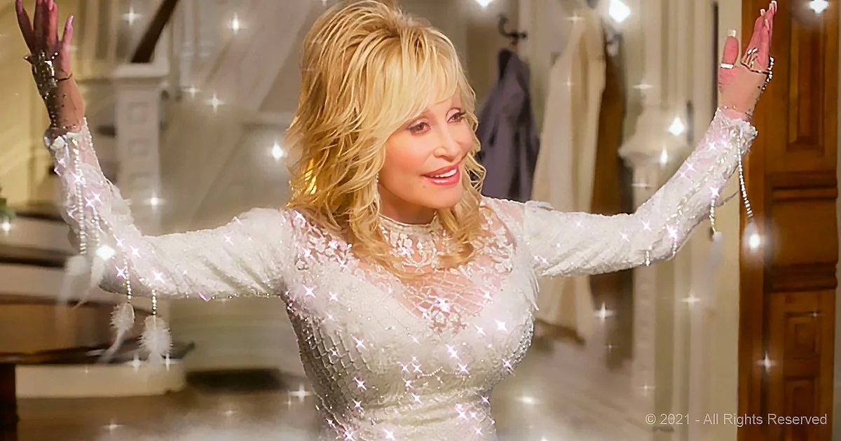 Dolly Parton in a sparkling white dress, arms raised, smiling, surrounded by twinkling lights.