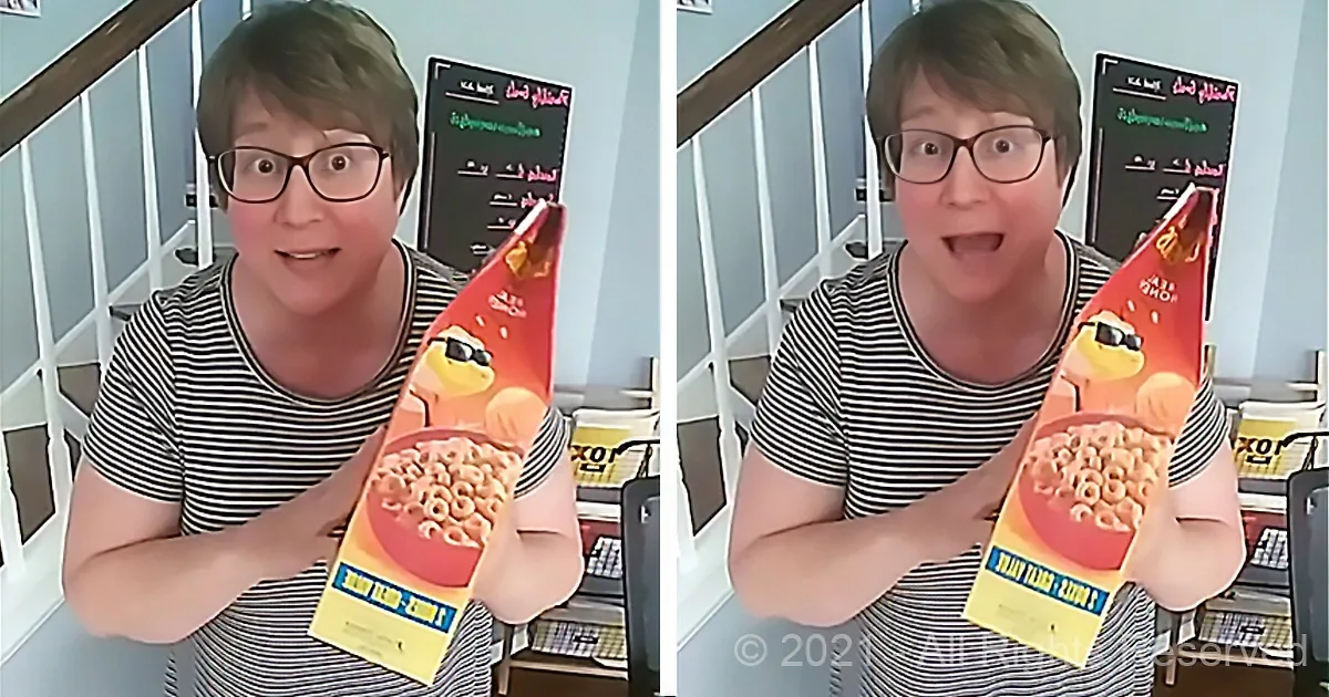 A person in a striped shirt holds a cereal box with a surprised expression, standing in front of a staircase.