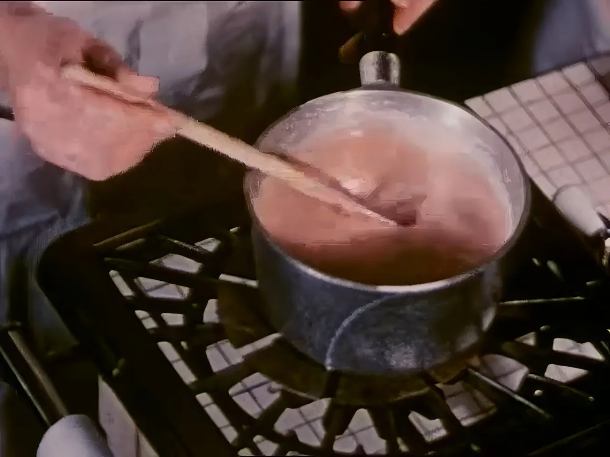 A person stirs a pot on a stove with a wooden spoon.