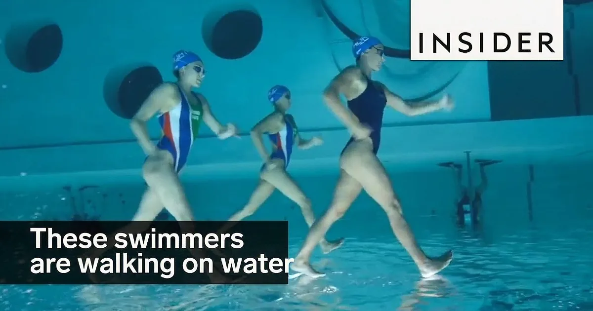 Three synchronized swimmers in blue and red outfits perform a routine in a pool.