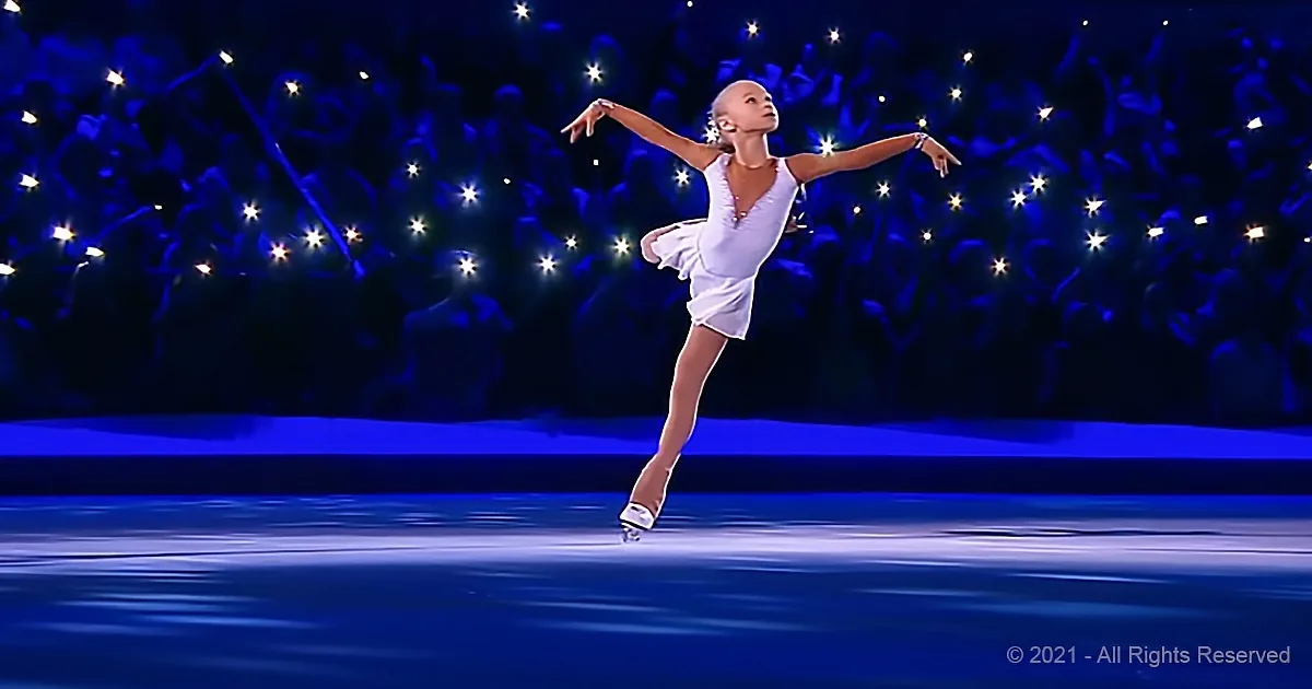 A figure skater in a white dress glides gracefully on ice, arms outstretched, against a backdrop of glowing spectators.
