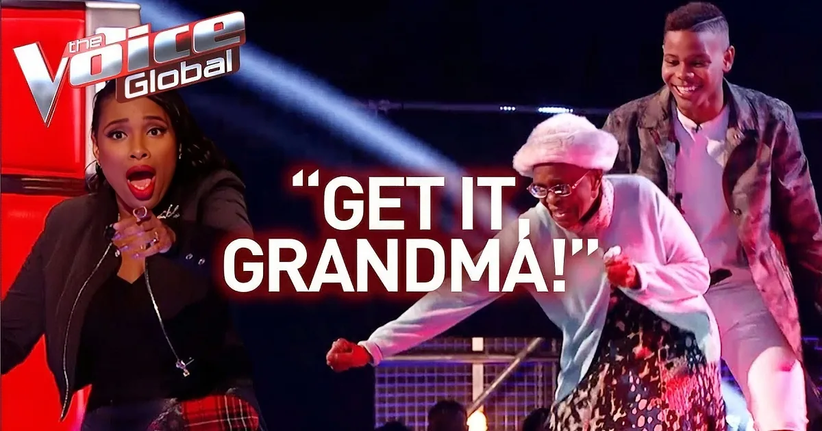 An elderly woman in a white outfit dances joyfully on stage with a younger man in a patterned suit.
