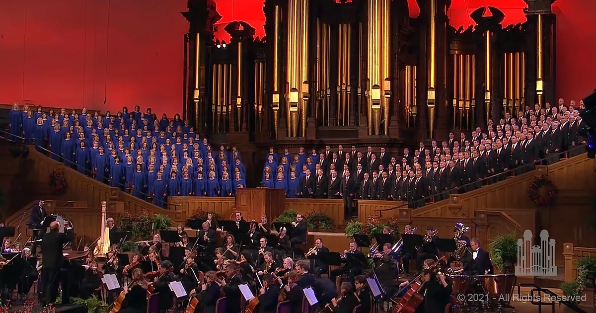 A grand choir in blue robes and an orchestra with a conductor in a large, ornate hall with a large organ.