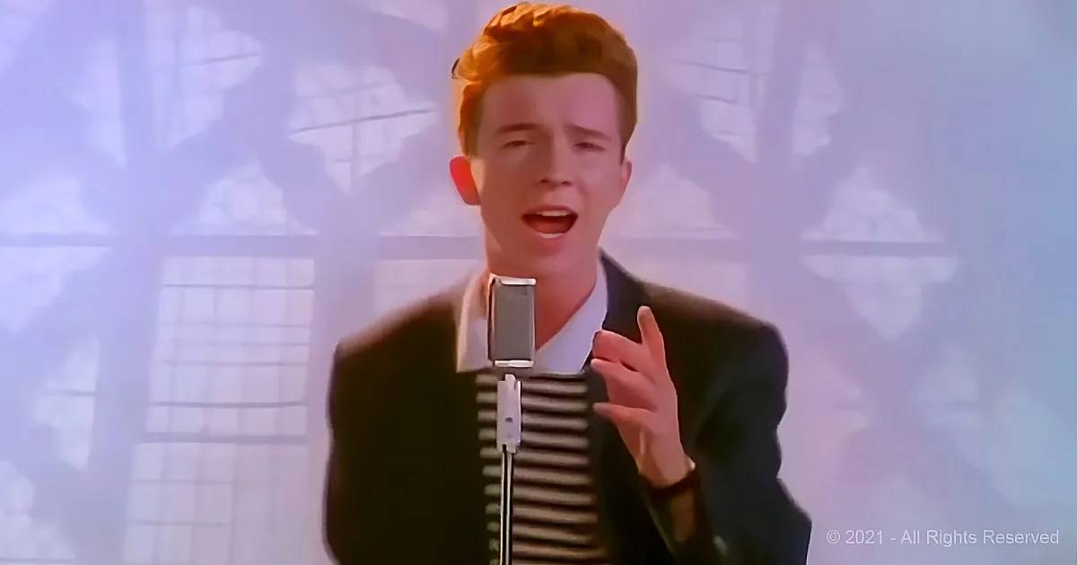 A person in a suit sings into a microphone, gesturing with their hand.