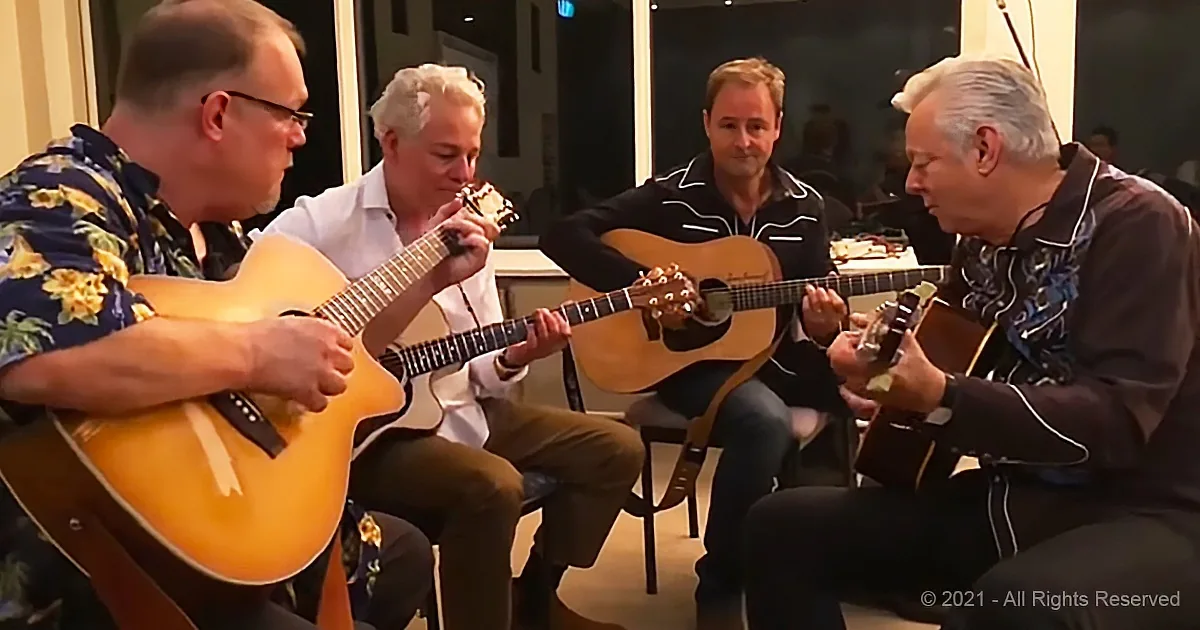 Four men are playing acoustic guitars together in a room.