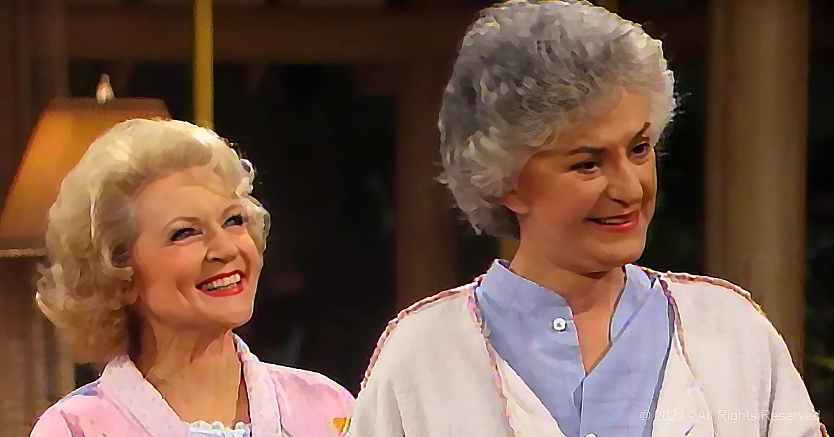 Two women with curly white hair, one in pink, the other in white, smiling and looking to the side.