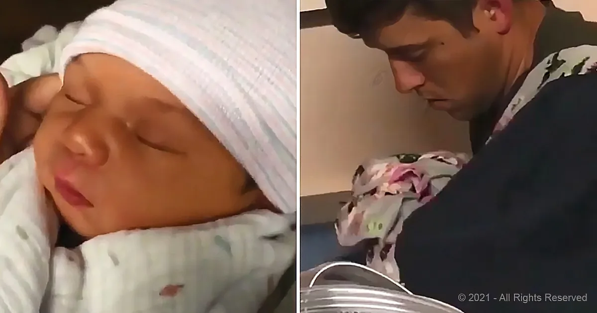 A newborn baby wrapped in a white blanket, wearing a striped hat, is being held by a man who is looking down at the baby.