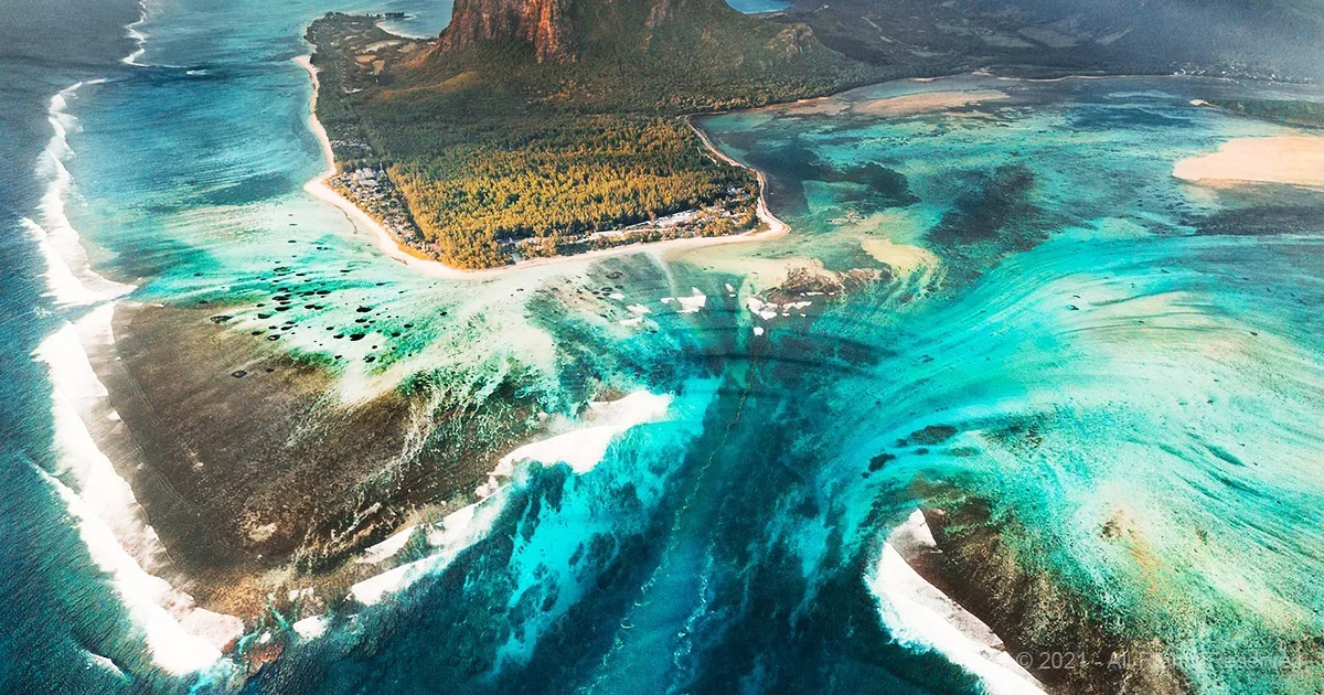 Aerial view of a tropical island with turquoise waters, sandy beaches, and lush greenery.